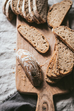 From above of crispy pieces of delicious bread arranged on wooden chopping board on table in kitchen