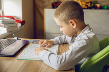 Naklejka premium The boy does his homework at home. Online training.