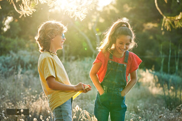 Ten-year-old boy and girl friends walking through the countryside on a sunny summer day in T-shirts and jeans