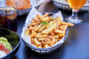 From above of black basket with french fries surrounded by snacks and beverages in cafe