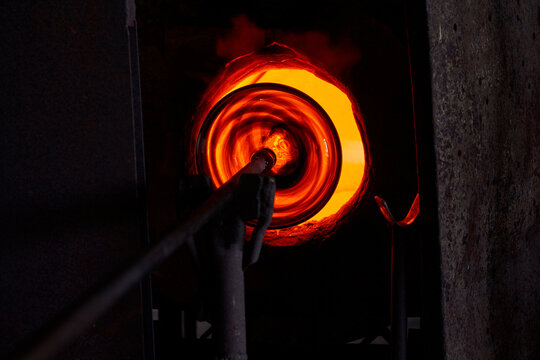 Blowpipe and melting glass in hot furnace in workshop