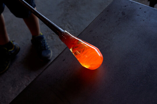 From above of burning hot liquid glass mass on blowpipe in process of producing shisha glass base