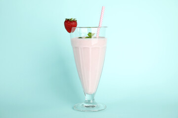 Tasty fresh milk shake with strawberry on light blue background