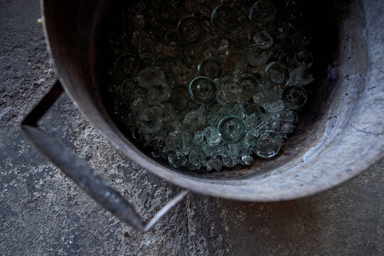 Top view of big metal barrel filled with assorted pieces of broken glass for future melting