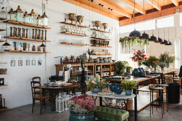 Interior of modern floral shop with various bouquets and decorative pots and vases arranged on wooden counters and shelves inside spacious pavilion