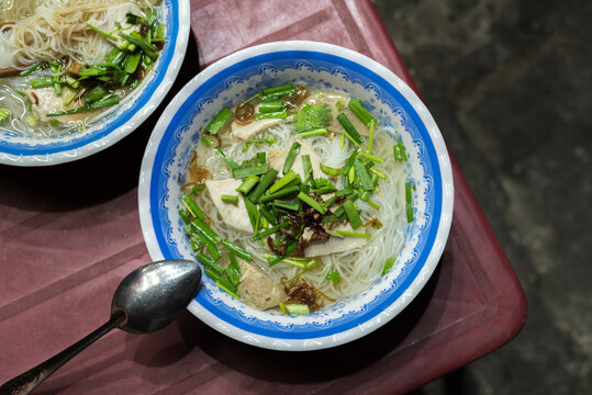  Soup called hu tieu go (noodle, meat products, herbs) on a shabby red plastic table in the street in Ho Chi Minh City, for 15 000 dongs (0.65 USD) a bowl. A budget food popular in Saigon, Vietnam.