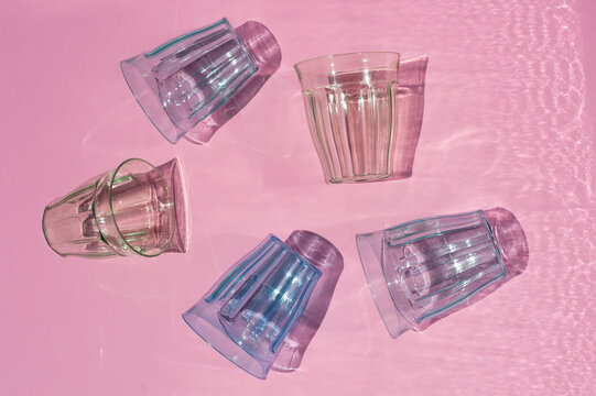 From above of assorted colorful glassware casting shadow placed on pink background in studio