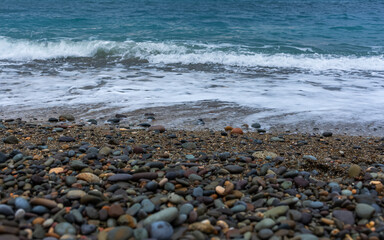 Pebble beach and turquoise water. Texture of water and a pebble. Beach with clear and clear water view from above.