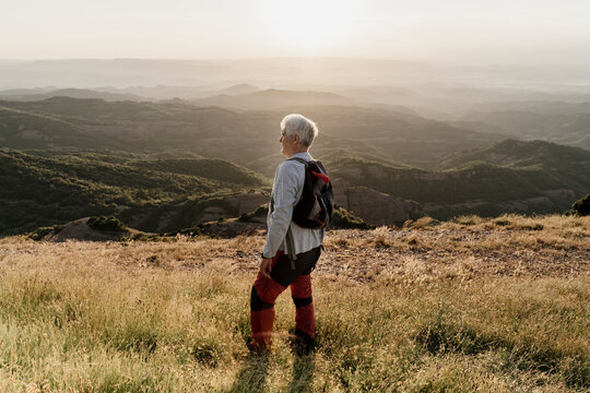 Active senior man standing on mountain while looking at landscape during sunset