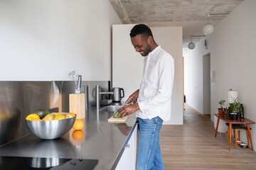 Smiling man slicing avocado in kitchen