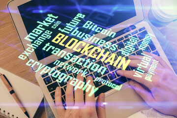 Double exposure of man's hands typing over computer keyboard and crypto currency theme hologram...