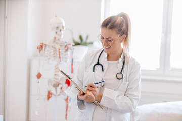 Portrait of smiling female doctor with anatomical skeleton in the background