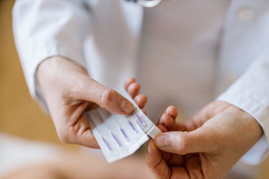 Acupuncture, female alternative practitioner opening package with acupunture needle
