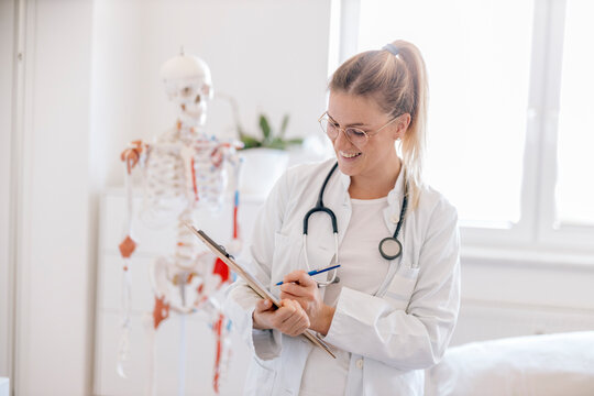 Portrait of smiling female doctor with anatomical skeleton in the background