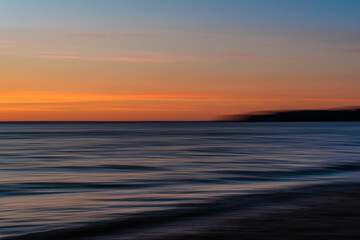 Fototapeta premium abstract of sunset in the sea, with mountains in the distance. 
