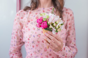 Obraz na płótnie Canvas Women in vintage dress holding ice cream waffle cone with pink roses and hydrangea .Floral composition of beautiful spring fresh flowers isolated indoor. Florist at work.Copy Space.Food photo.