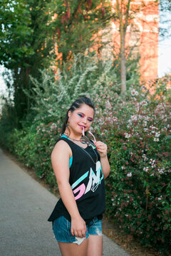 Teenager girl with down syndrome wearing 80's colorful make-up and clothes looking at camera