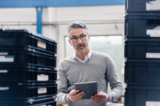 Thoughtful male supervisor holding digital tablet in factory