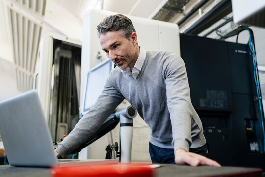Mature male supervisor using laptop in industry
