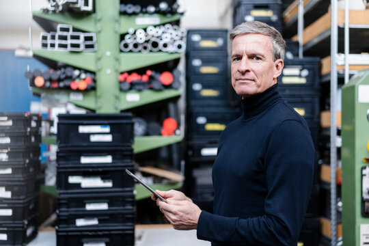 Confident male supervisor holding digital tablet in factory