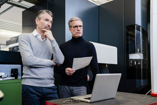 Pensive male supervisors discussing in factory