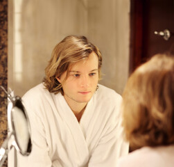 young man looking in the mirror,combing his hair,looking at problems on face