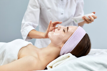 beautician applies the mask to the face of beautiful woman in the spa salon. spa treatments