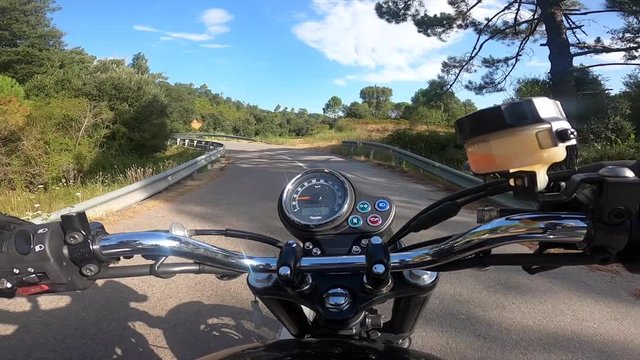 Riding an old black motorbike on a curly asphalt tarmac road driver point of view