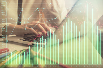Double exposure of woman hands typing on computer and financial graph hologram drawing. Stock...