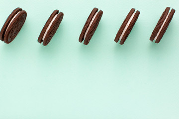 Sweet brown cookies with white cream inside on bright blue background at the top. Close up with copy space. Homemade and bakery concept