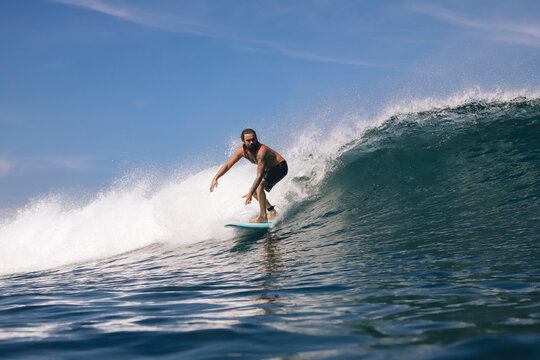 Shirtless mid adult man surfing on sea against sky, Bali, Indonesia