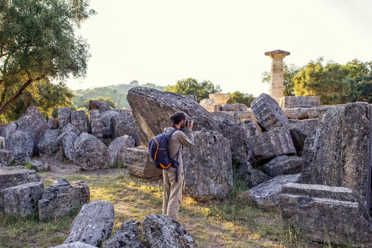 Greece,&Ocirc;&oslash;&Omega;Olympia, Male tourist photographing ruins of ancient Temple of Zeus at sunset