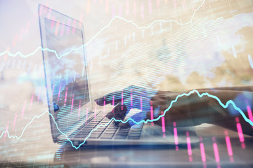 Double exposure of woman hands typing on computer and forex chart hologram drawing. Stock market invest concept.
