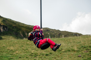 Cute child blond girl rides on play equipment in a children's playground. Reuniting with nature. Childhood, lifestyle. 