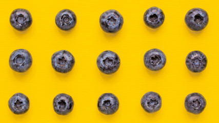 Macro pattern shot blueberry on bright yellow background from adobe. Food and vegetarian concept with copy space