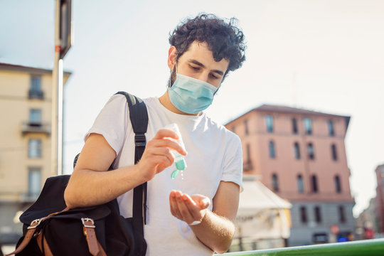 Man Wearing Face Mask Washing Hands With Sanitizer While Standing Against Clear Sky