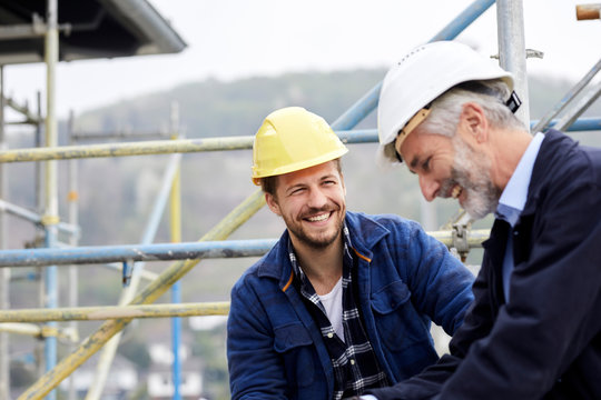 Happy architect and worker on scaffolding on a construction site