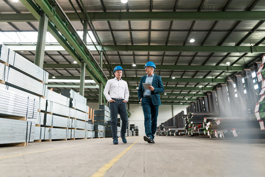 Two businessmen having a meeting and walking in a factory