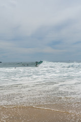 Fototapeta na wymiar Surfers on the sea, turquoise water, blue sky. Arugam Bay, Sri Lanka. Portrait format