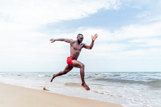 Athletic man running on beach - Powered by Adobe