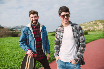 Smiling male friends standing on footpath against cloudy sky in park