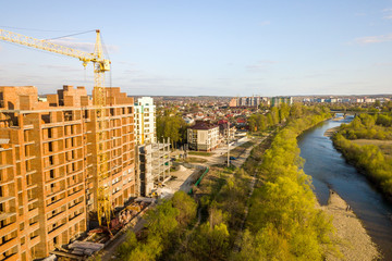 Fototapeta premium Aerial view of tall residential apartment buildings under construction and Bystrytsia river in Ivano-Frankivsk city, Ukraine.