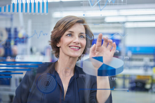 Happy female manager touching line graph on glass in industry