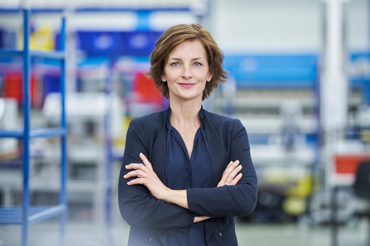 Confident female manager standing arms crossed in factory