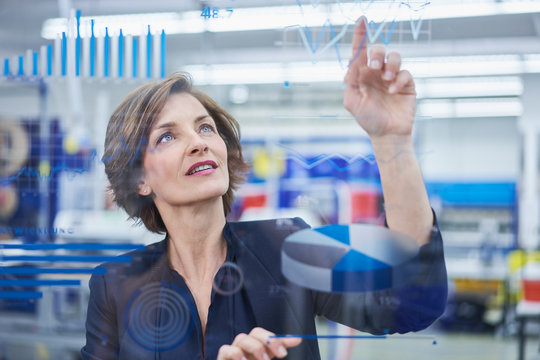 Female manager touching line graph on glass in industry