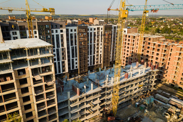 High multi storey residential apartment buildings under construction. Concrete and brick framing of high rise housing. Real estate development in urban area.