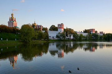 Fototapeta na wymiar Novodevichy Convent behind the Big Novodevichy Pond in the reflections of the setting sun