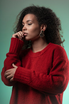 Thoughtful young woman with curly hair standing against blue background