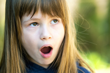 Portrait of surprised child girl outdoors in summer. Shocked female kid on a warm day outside.