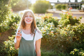 Portrait of smiling young woman in public garden at backlight